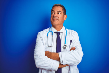 Handsome middle age doctor man wearing stethoscope over isolated blue background smiling looking to the side and staring away thinking.