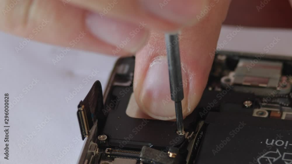 Poster extreme close up of hand using small tool to screw tiny screw into smartphone component.j.a