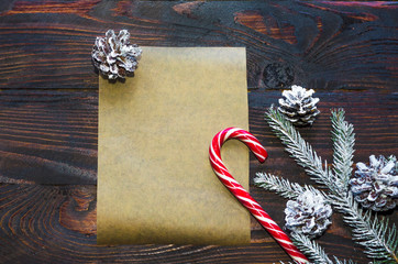 Christmas layout, spruce branch with cones, with snow, candy, new year congratulations to colleagues on dark wooden dackground, make a wish, letter to Santa.  Flat lay, top view, copy space for text.