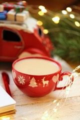 Christmas time. Christmas tea in a red cup, red decorative machine, red wooden tree,  garland on shabby chic background.Winter holidays.