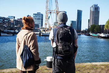 Rolgordijnen Young couple tourists looking and pointing to Rotterdam city harbour, future architecture concept, industrial lifestyle people © iordani