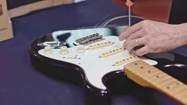 Guitarist unscrew pickguard from guitar body