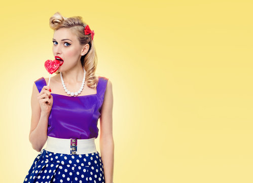 Woman eating colourful lollipop, dressed in pinup style