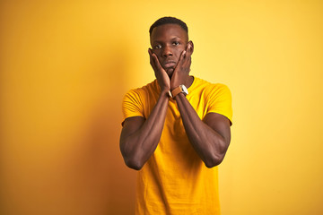 Young african american man wearing casual t-shirt standing over isolated yellow background Tired hands covering face, depression and sadness, upset and irritated for problem