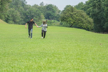 Fototapeta na wymiar Young playful young muslim Asian couple running together hand by hand on natural background