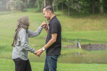 Asian young Muslim couples are enjoying being together by dancing in the open green area