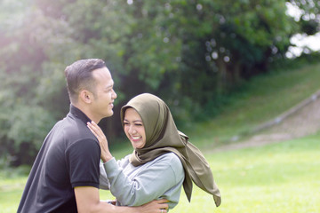 Obraz premium Outdoors photo, beautiful, young muslim couple, hugging and kissing and being affectionate with each other. nature in the background.