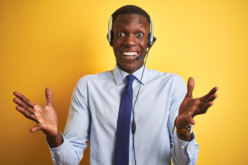 African american operator man working using headset over isolated yellow background celebrating crazy and amazed for success with arms raised and open eyes screaming excited. Winner concept