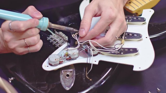 Guitarist soldering electric guitar components