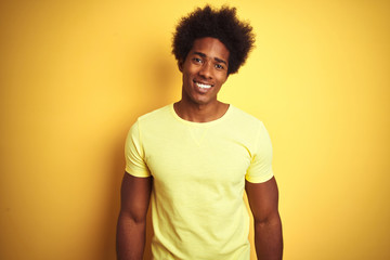 Fototapeta na wymiar African american man with afro hair wearing t-shirt standing over isolated yellow background with a happy and cool smile on face. Lucky person.