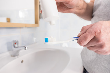 Person putting toothpaste on toothbrush