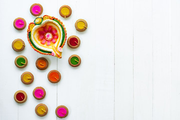 Happy Diwali - Clay Diya lamps lit during Dipavali, Hindu festival of lights celebration. Colorful traditional oil lamp diya on white wooden background