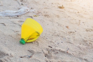 Fototapeta na wymiar Yellow Plastic bottle on Beach Pollution Environment