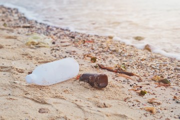 Waste plastic bottles and other types of plastic waste on beach.