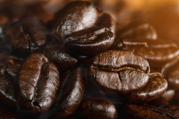 closeup background of roasted arabica coffee beans with aroma smoke