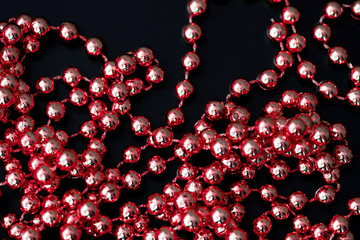 Shiny red garland on a dark surface close up. Abstract christmas background