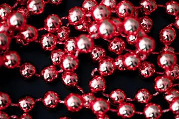 Shiny red garland on a dark surface close up. Abstract christmas background