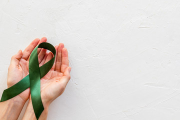 Jade ribbon in hands as symbol of disease control on white background top view copy space