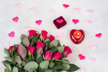 a bouquet of red roses, a velvet box for the ring, satin hearts, a candlestick with a candle