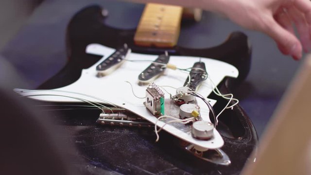 Luthier soldering wires of a broken guitar