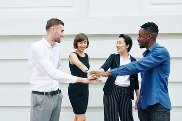 Cheerful business colleagues stacking hands to express unity and support