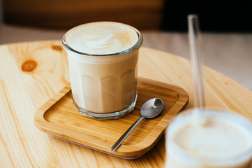 Hot cappuccino in a transparent glass on light wooden table