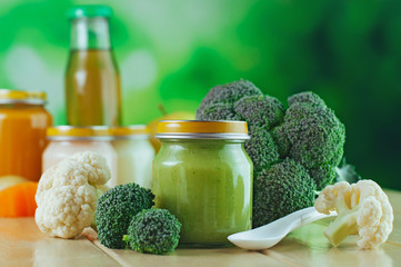 Jar with broccoli and cauliflower puree near fresh vegetables
