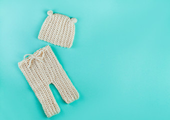 Small hat and pants for newborn baby on mint background