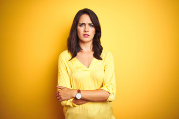 Beautiful elegant woman standing over yellow isolated background skeptic and nervous, disapproving...