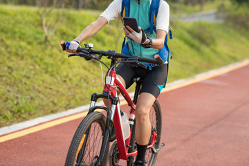 Riding on park bike path,using smartphone while riding bike on sunny day