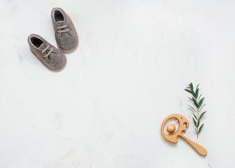 Newborn baby shoes and wooden beanbag on light marble background