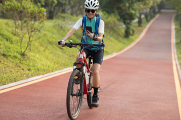 Riding on park bike path,using smartphone while riding bike on sunny day