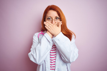 Young redhead doctor woman wearing glasses over pink isolated background shocked covering mouth with hands for mistake. Secret concept.