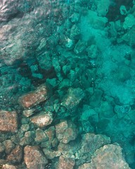 Aerial over water with visibility to bottom. Rocks underwater, turquoise Mediterranean Sea
