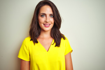 Young beautiful woman wearing yellow t-shirt standing over white isolated background with a happy and cool smile on face. Lucky person.