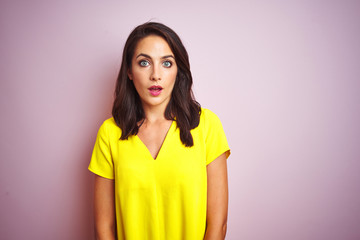 Fototapeta premium Young beautiful woman wearing yellow t-shirt standing over pink isolated background afraid and shocked with surprise expression, fear and excited face.