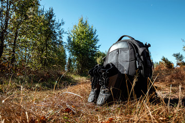 Camping backpack and boots on a background of summer nature. Trekking and camping adventures, hiking, hiking, traveling.