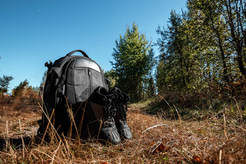 Camping backpack and boots on a background of summer nature. Trekking and camping adventures, hiking, hiking, traveling.