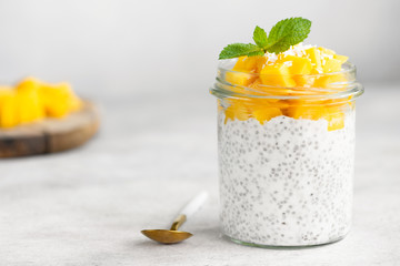 Chia pudding with mango in jar on grey concrete background. Clean eating concept, healthy...