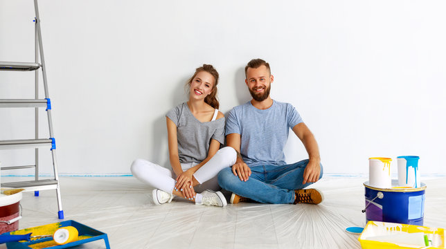 young happy couple is repairing and painting   wall at home