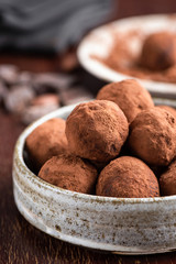 Chocolate truffles pile in a bowl covered in raw cocoa powder. Healthy vegan chocolate truffles, energy balls. Closeup view