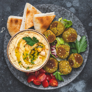 Hummus with falafel and pita bread on plate. Arabic cuisine appetizer. Top view, square composition