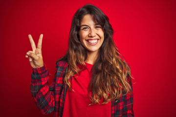 Young beautiful woman wearing casual jacket standing over red isolated background smiling doing phone gesture with hand and fingers like talking on the telephone. Communicating concepts.