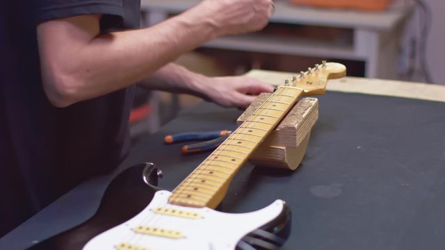 Guitarist wrap strings with a peg
