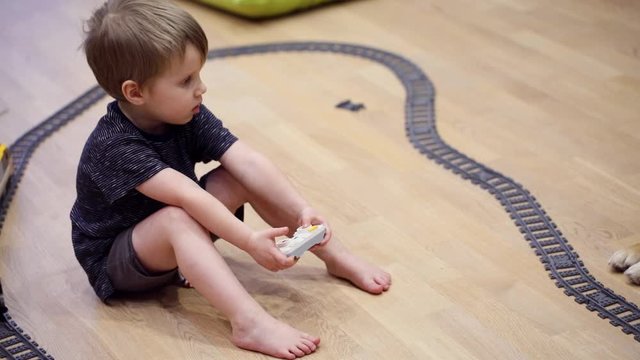 Four years old sad child boy play with radio train, constructed toy railroad at home. Toddler boy playing. Educational toys for preschool and kindergarten child, indoor playground, lifestyle concept