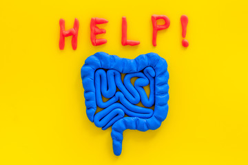 Intestines illness and treatment. Word help near guts on yellow background top view copy space