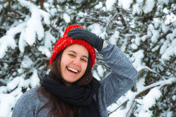 Fototapeta na wymiar portrait of young smiling woman in winter clothes in red hat with bubo fir tree in background