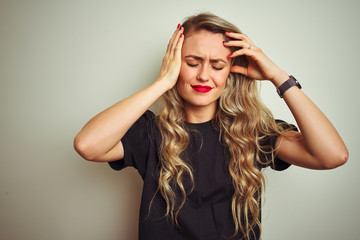 Young beautiful woman wearing black t-shirt standing over white isolated background suffering from headache desperate and stressed because pain and migraine. Hands on head.