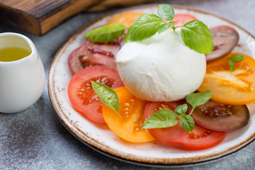 Close-up of caprese salad with different types of tomatoes, mozzarella and green basil leaves,...