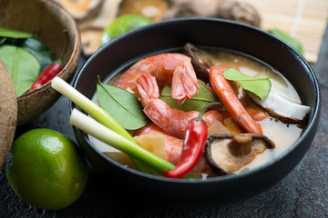 Close-up of a black bowl with traditional thai Tom Yum soup, selective focus